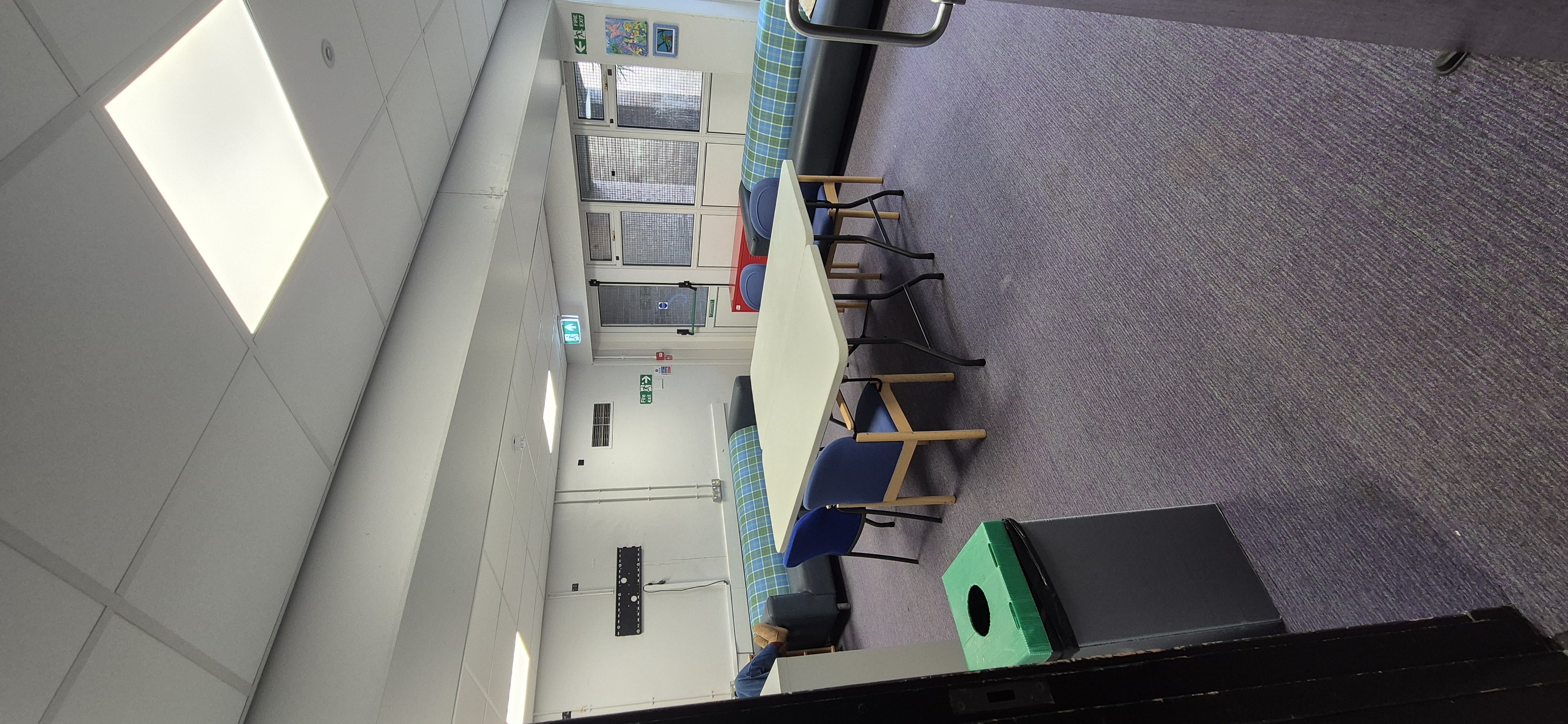 Adult Lounge at Whitburn Community Centre — comfortable carpeted room with tartan bench seating and a central table, suitable for group meetings and social gatherings